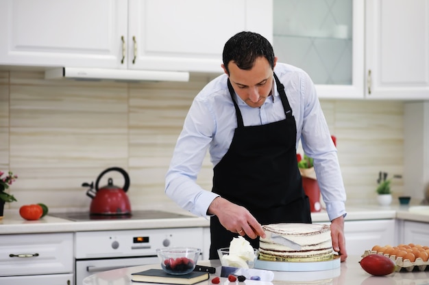 책상 앞의 마스터 페이스트리 셰프. 집에서 디저트 요리하기. 아르메니아 남자는 제과에 종사하고 있습니다.