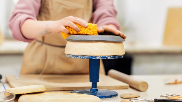 Il maestro di scolpire la ceramica lavora in uno studio dando una forma arrotondata agli strumenti di argilla