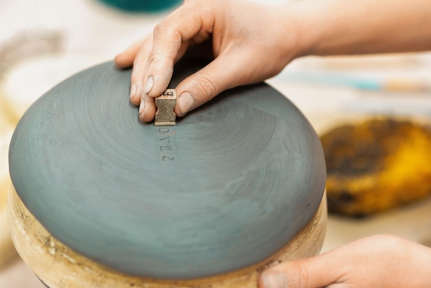 Foto gratuita il maestro della scultura in ceramica che lavora in uno studio che stampa un'iscrizione su un'argilla