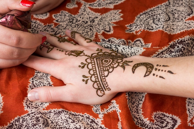 Master tattooing mehndi on woman hand