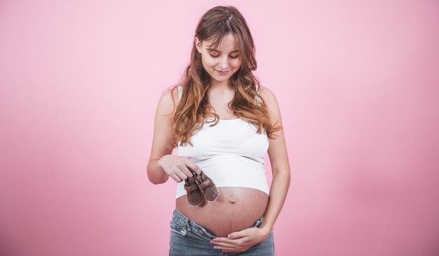 Maternity concept, pregnant woman with baby slippers in hands