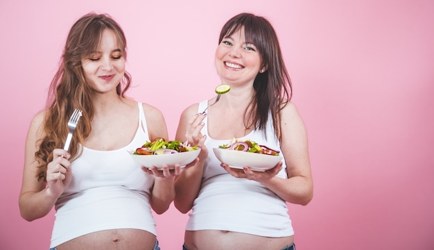 マタニティコンセプト、新鮮なサラダを食べる2人の妊娠中の女性