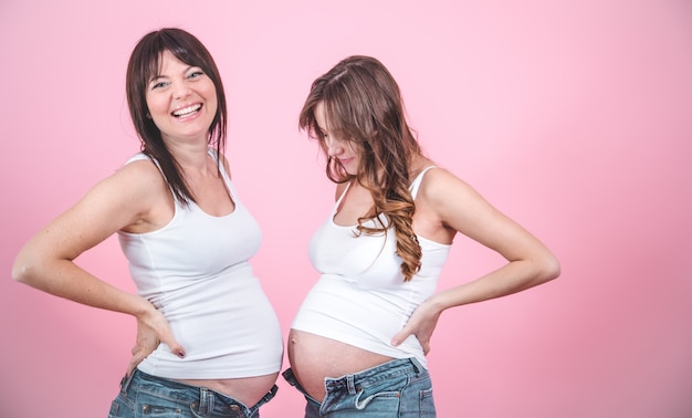 Maternity concept, two pregnant women with an uncovered tummy Free Photo