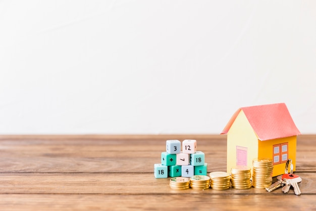 Free photo math blocks, house, key and stacked coins on wooden surface