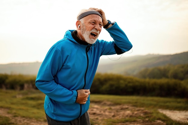 Зрелый спортивный мужчина страдает от головной боли во время пробежки на природе