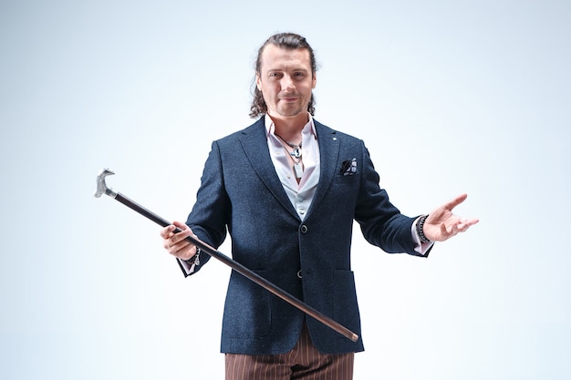 The mature barded man in a suit holding cane.