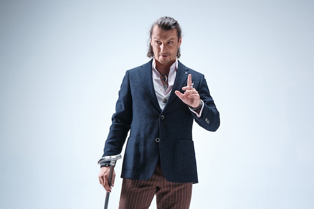 The mature barded man in a suit holding cane.