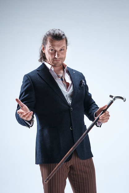 The mature bearded man in a suit holding cane.