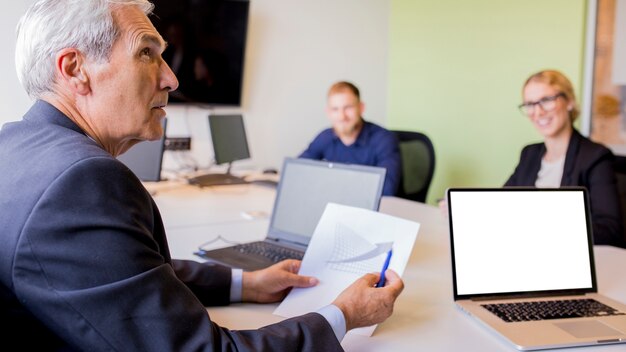 Mature businessman showing graph in the business meeting