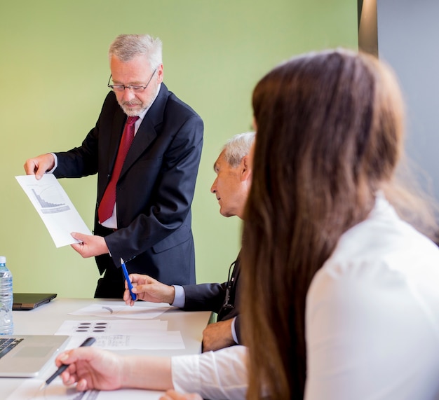 Free photo mature businessman showing graph to his business partner in the office