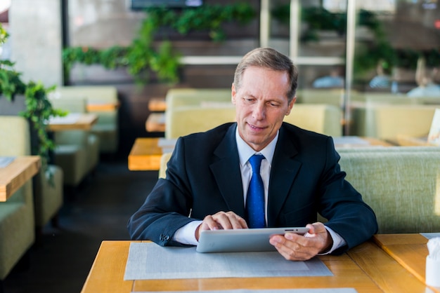 Mature businessman using digital tablet in restaurant