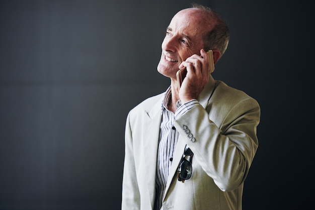 Mature Caucasian businessman posing in studio and talking on mobile phone
