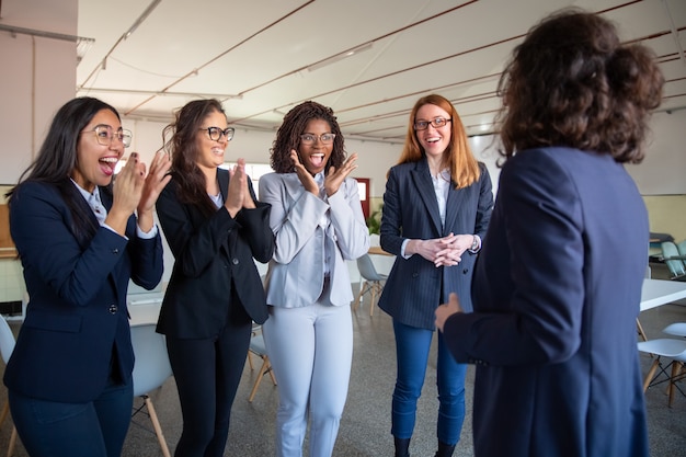 Mature colleague talking to happy younger colleagues