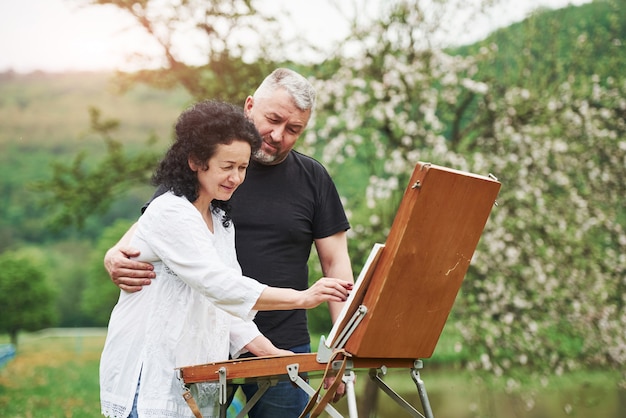 Mature couple have leisure days and working on the paint together in the park