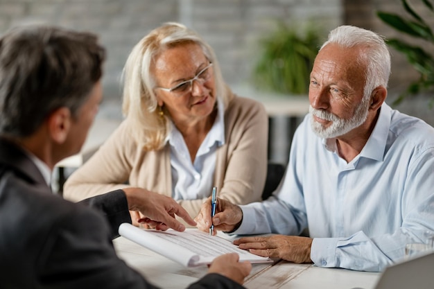 Free photo mature couple having a meeting with bank manager and signing lease agreement in the office focus is mature man