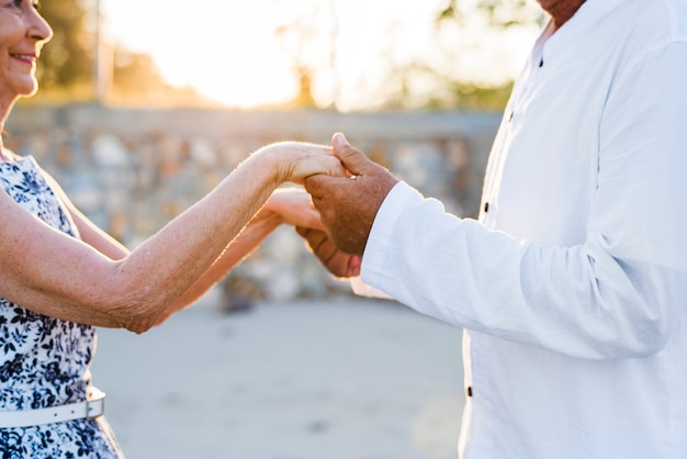 Free photo mature couple holding hands in the sunset