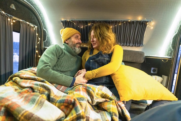 Mature couple indoor in camper traveling together Retired people on romantic mini camper round trip enjoying time together Middle aged couple wake up or off to bed winter vacation