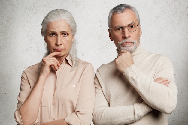 Mature couple posing against concrete wall