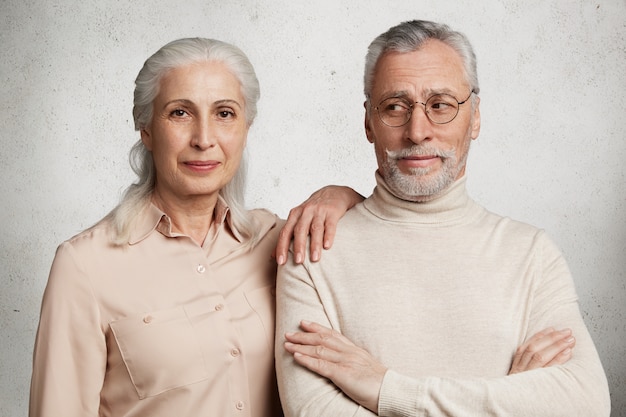 Free photo mature couple posing against concrete wall