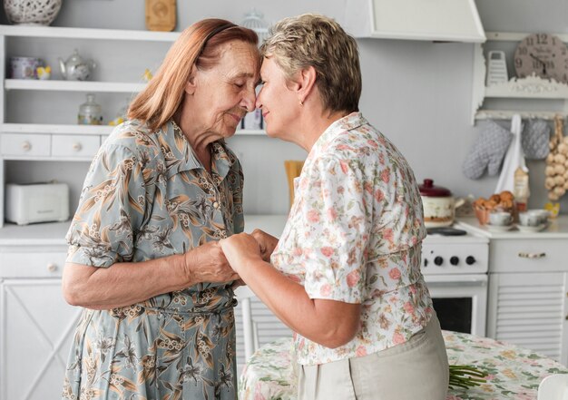 Mature daughter consoling her senior mother holding hand at home