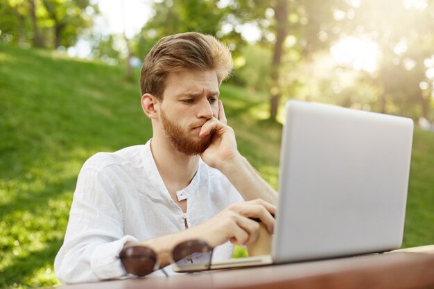 Mature ginger handsome man with laptop computer in the park