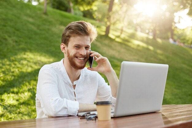 Mature ginger handsome man with laptop computer in the park