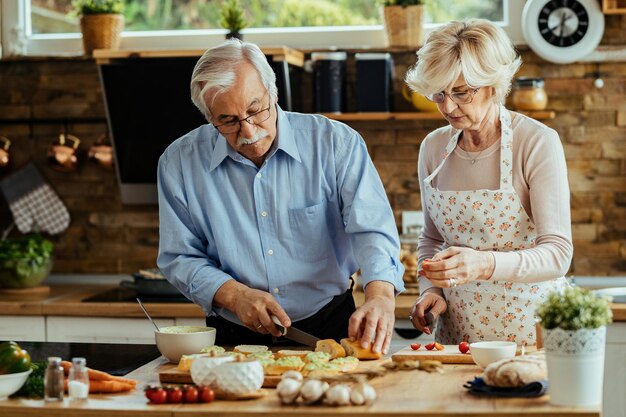Зрелые муж и жена готовят брускетту на кухне