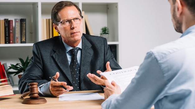 Mature lawyer discussing contract with client in the courtroom