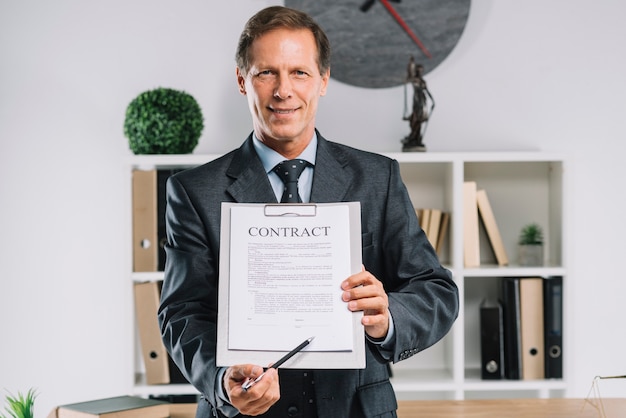 Mature lawyer pointing at signature place on a contract document with pen