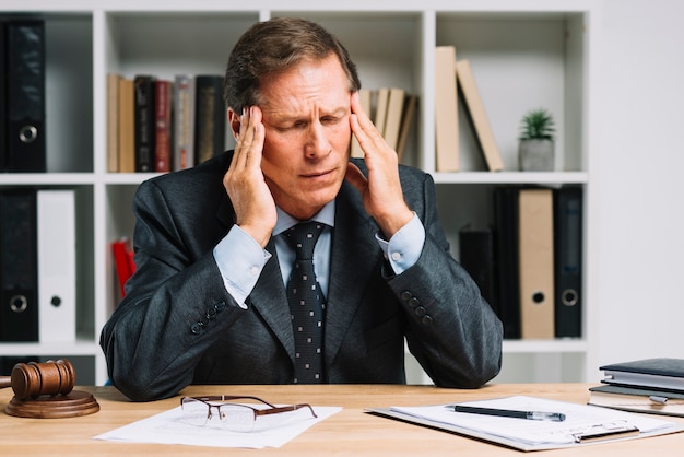 Free photo mature lawyer with headache sitting in the courtroom