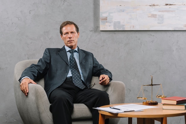 Free photo mature male lawyer sitting on armchair in the courtroom