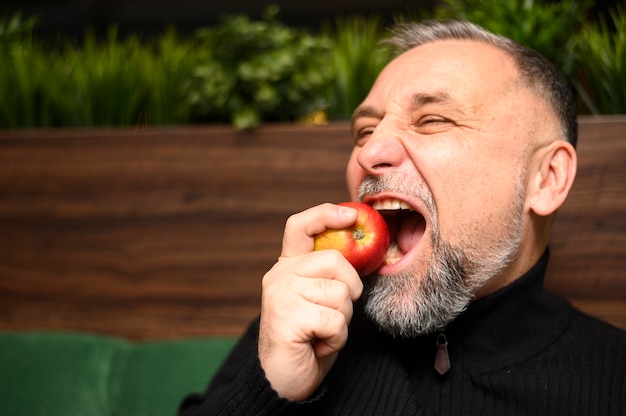 Free photo mature man eating an apple