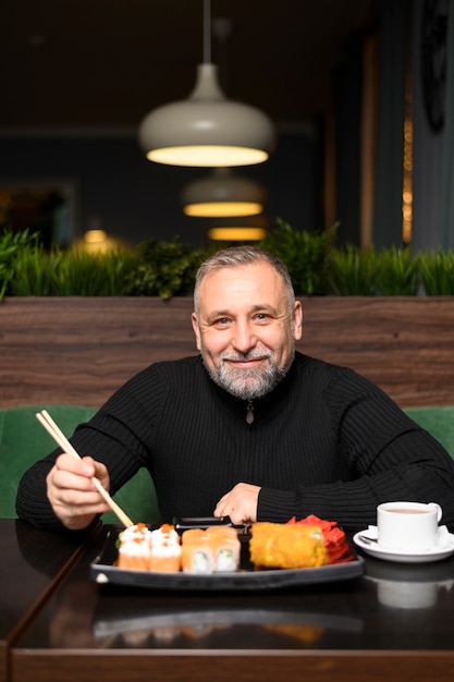 Free photo mature man eating in a sushi restaurant