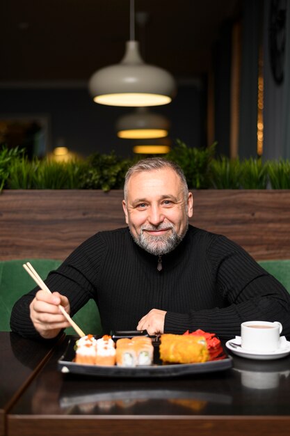 Mangiatore di uomini maturo in un ristorante di sushi