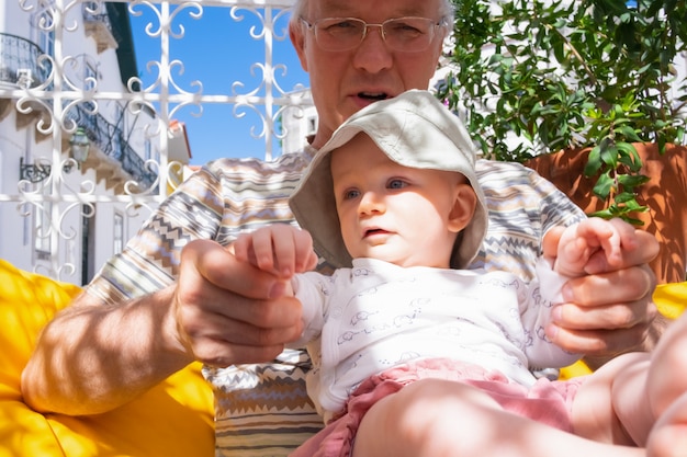 Зрелый мужчина держит внучку очаровательны младенца