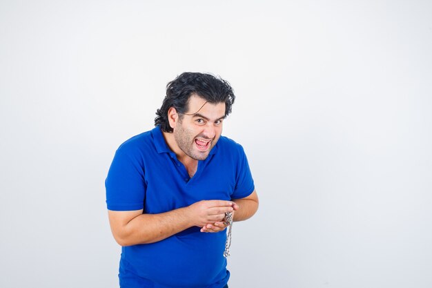 Mature man holding chain in blue t-shirt and looking happy , front view.