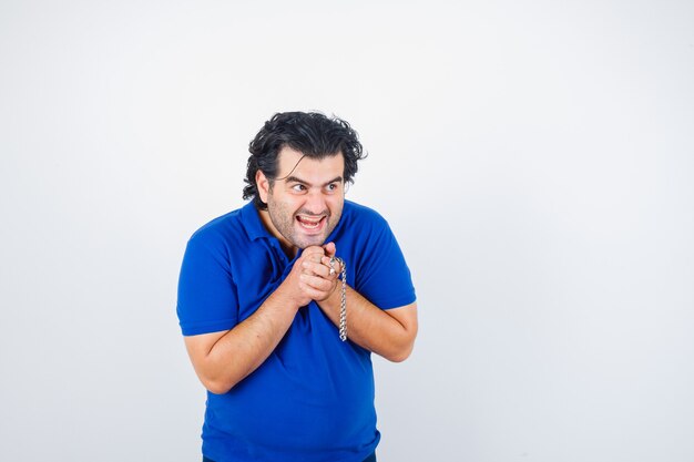 Mature man holding chain in blue t-shirt and looking happy. front view.