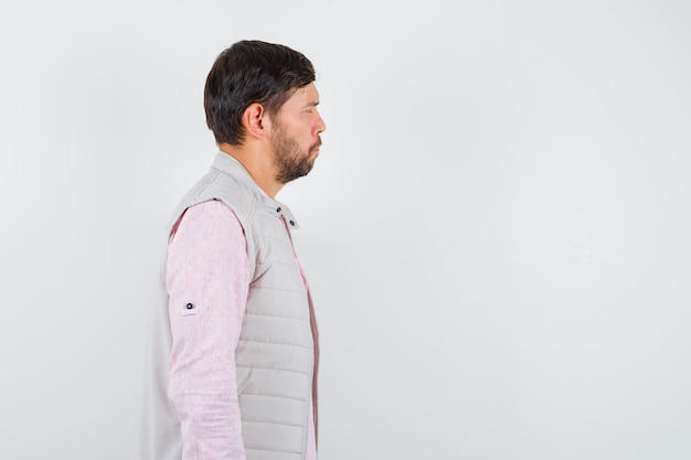 Mature man looking aside in shirt, sleeveless jacket and looking pensive .