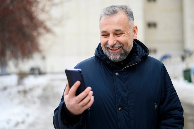 彼の携帯電話を屋外で見ている中年の男性