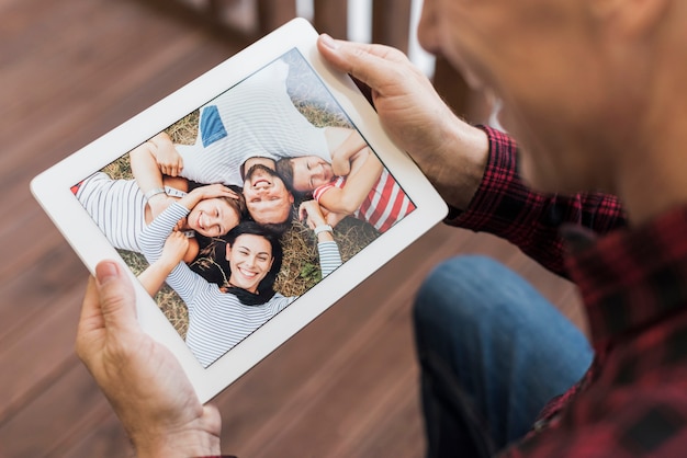 Mature man looking on photos with his children and grandchildren