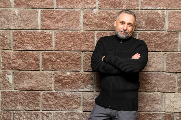 Mature man posing next to brick wall with copy space