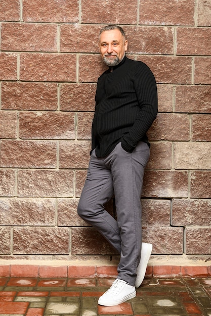 Mature man posing next to brick wall