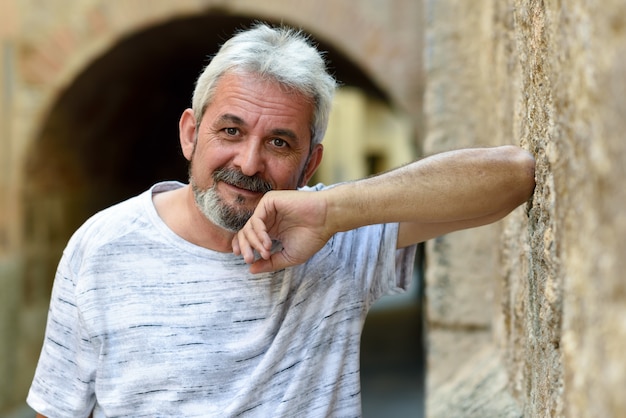 Free photo mature man smiling looking at camera in urban background