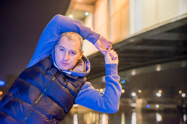 Mature man stretching outdoors. A handsome forties man is serious as he performs some stretching exercises.