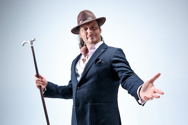 Free photo the mature man in a suit and hat holding cane.