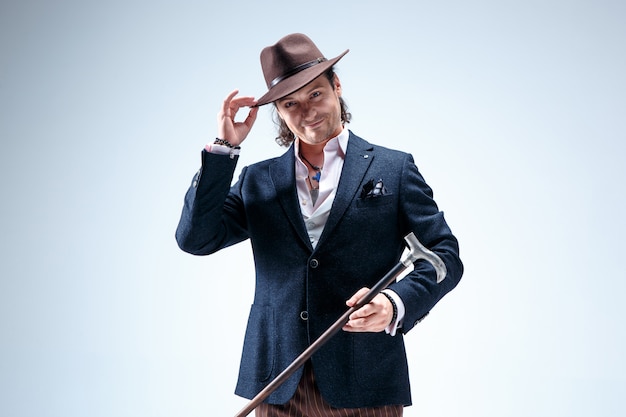 Free photo the mature man in a suit and hat holding cane.