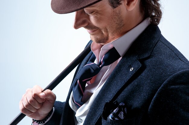 The mature man in a suit and hat holding cane.