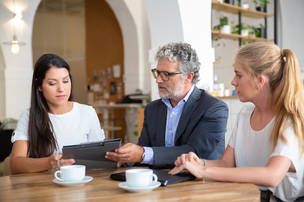 Professionista maturo che spiega i dettagli dell'accordo ai giovani clienti