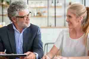 Free photo mature professional meeting with young customer at co-working, holding documents, talking and laughing