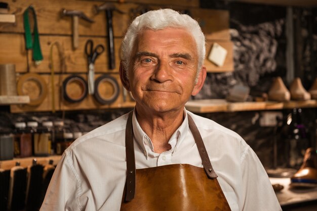 Mature smiling shoemaker in workshop